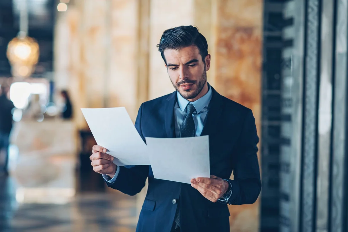 Attorney in a suit reading a printed document in the office