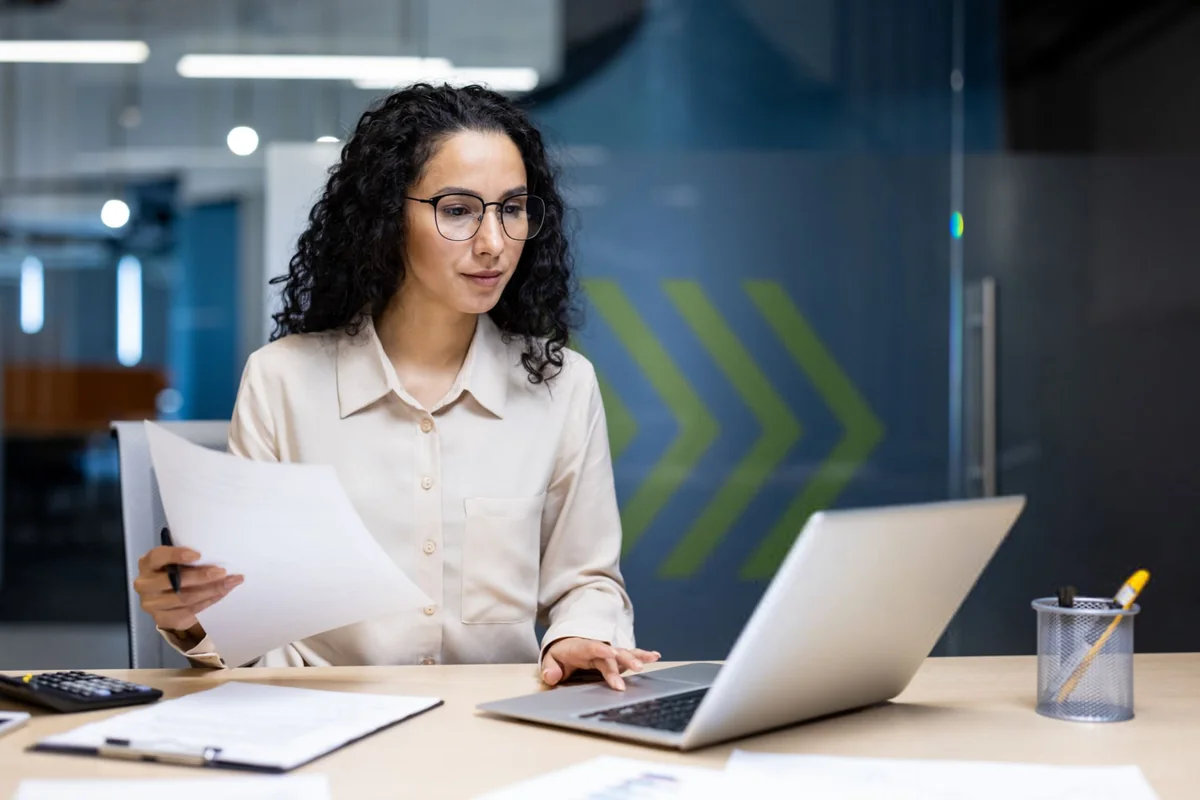 Paralegal reviewing a printed draft beside her laptop