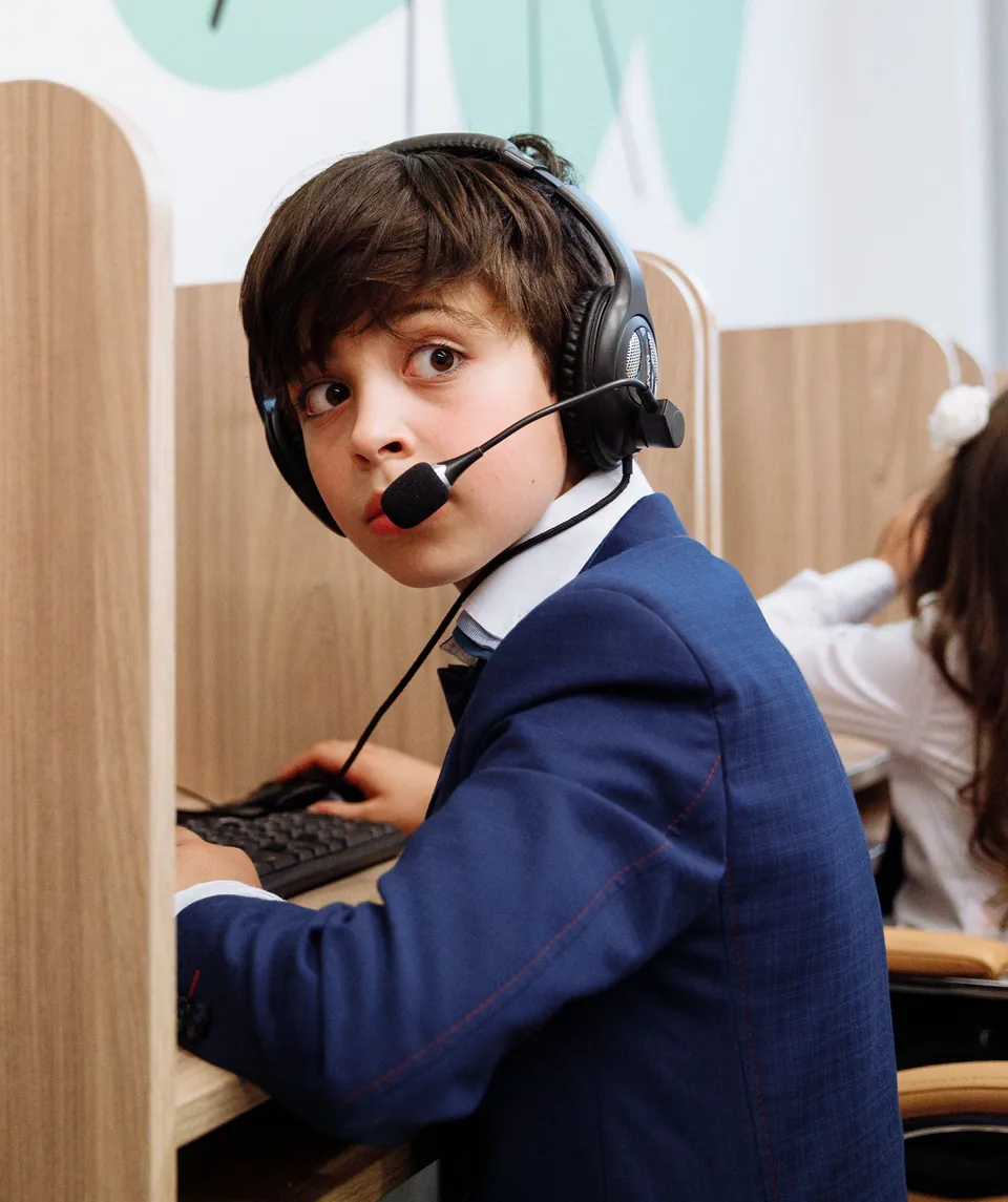Student wearing a headset microphone at a classroom computer