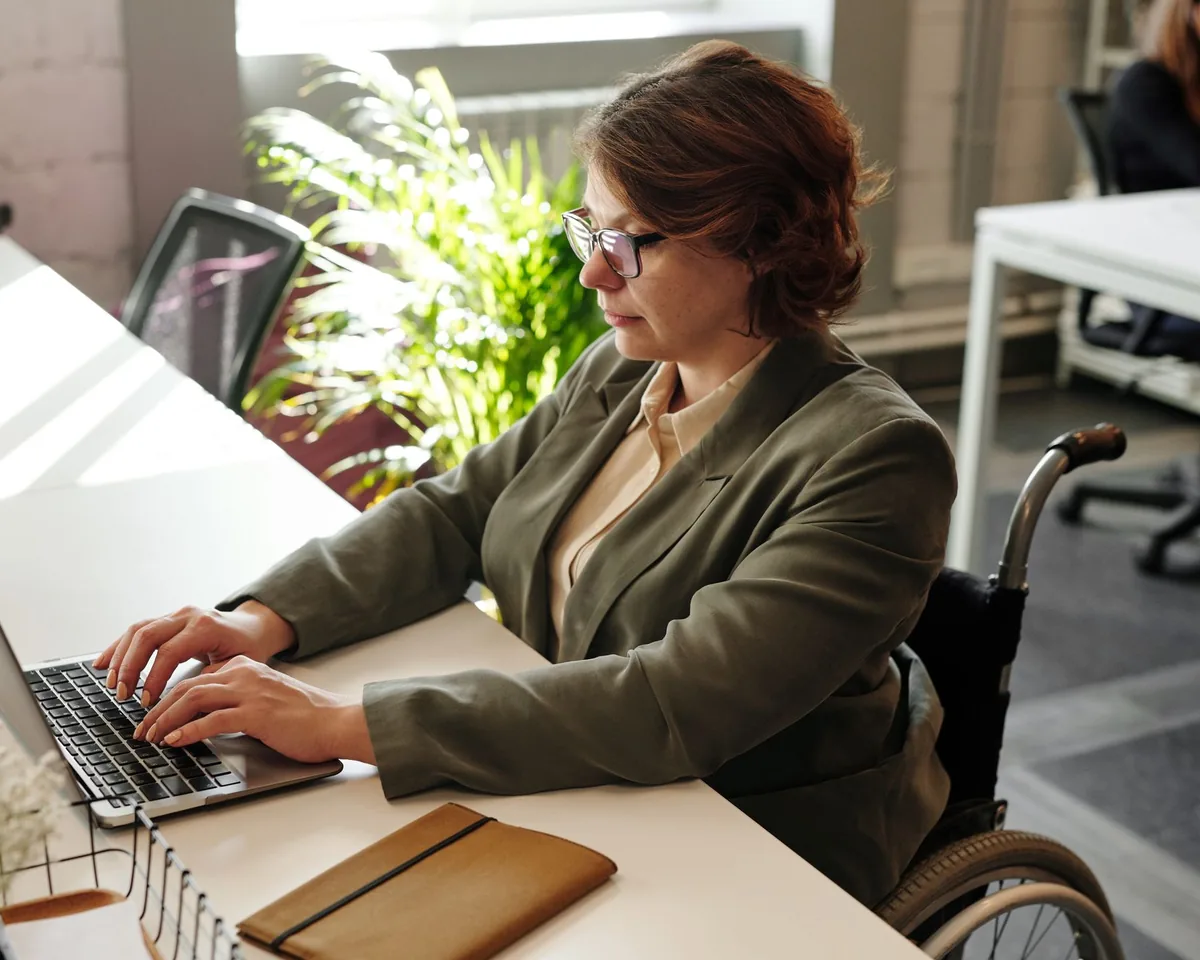Woman who uses a wheelchair working on a laptop at her office desk