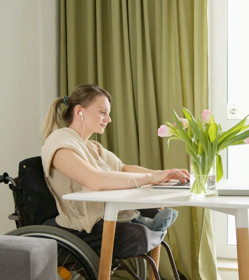 Woman who uses a wheelchair working on a laptop at a desk at home