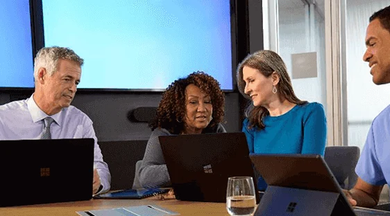Health system leaders meeting around a conference table with laptops