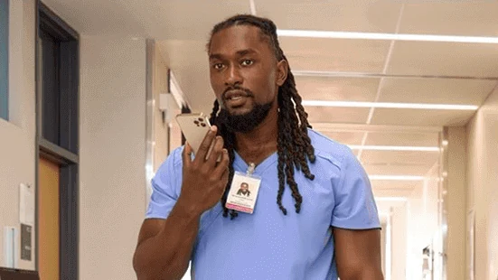 Nurse in blue scrubs dictating into a phone in a hospital hallway