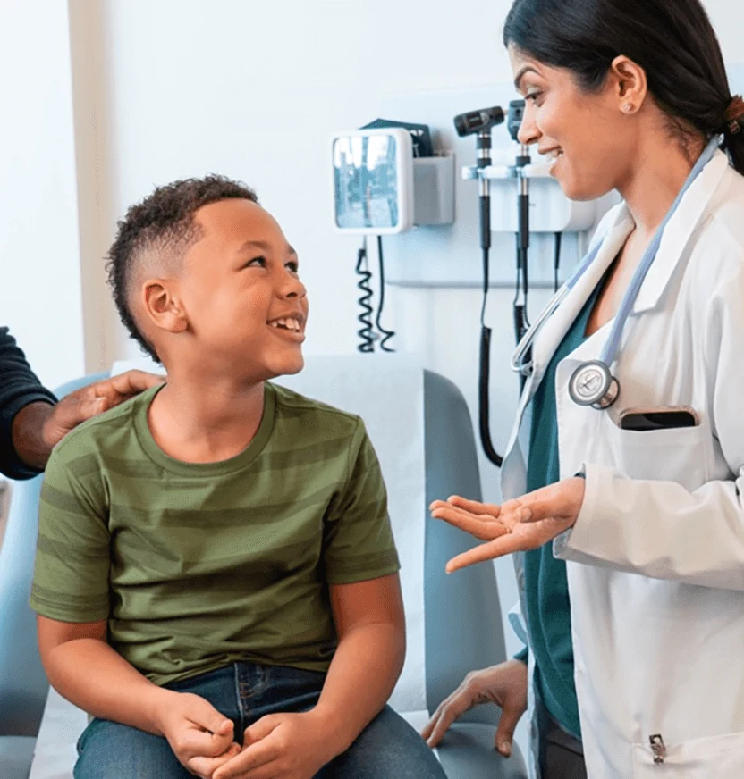Physician smiling and talking with a young patient in an exam room
